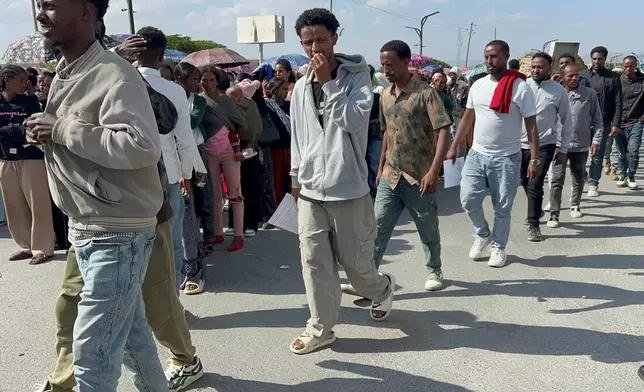 In this photo made with a smartphone, former Tigrayan fighters, some carrying documents, line up to register for a disarmament, demobilization and reintegration program in Mekelle, Ethiopia, Thursday, Oct. 15, 2026. The program has resumed after being suspended amid rising tensions between the Tigray People's Liberation Front and the federal government. (AP Photo/Filmon Equar Hailu)