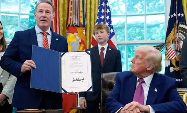 FILE - President Donald Trump listens as Sen. Jon Husted, R-Ohio, speaks while holding up a signed resolution in the Oval Office of the White House, May 9, 2025, in Washington. (AP Photo/Alex Brandon, File)