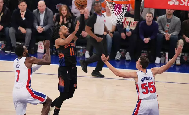 New York Knicks' Jalen Brunson (11) drives past Detroit Pistons' Paul Reed (7) and Duncan Robinson (55) during the first half of an NBA basketball game Tuesday, Oct. 27, 2026, in New York. (AP Photo/Frank Franklin II)
