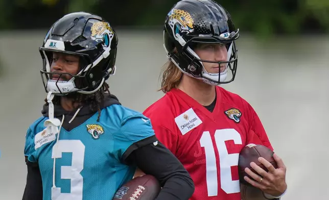 Jacksonville Jaguars' quarterback Trevor Lawrence (16), right, and wide receiver Jakobi Meyers (3) work out during an NFL football practice in Hertfordshire, England, Wednesday, Oct. 14, 2026. (AP Photo/Kin Cheung)