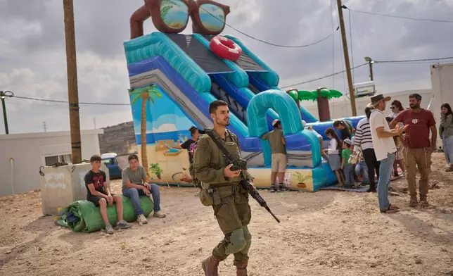 An Israeli soldier looks on as Israeli settlers celebrate the inauguration of a newly built synagogue at the illegal Gad Natan outpost in the occupied West Bank, Tuesday, Sept. 29, 2026. (AP Photo/Ohad Zwigenberg)