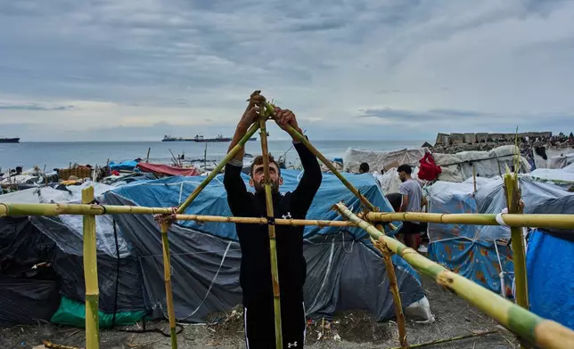 A migrant from Morocco builds a makeshift tent on El Trampolin Beach in the Spanish enclave of Ceuta, Monday, Sept. 28, 2026. (AP Photo/Bernat Armangue)