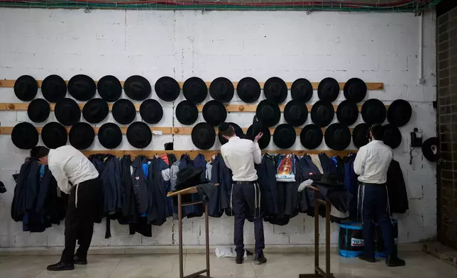 Ultra-Orthodox Jewish seminary students hang their hats and jackets before having lunch in the dining hall at at Ponevezh, Israel’s most prominent yeshiva, or seminary, in Bnei Brak, Israel, Wednesday, Feb. 11, 2026. (AP Photo/Ohad Zwigenberg)