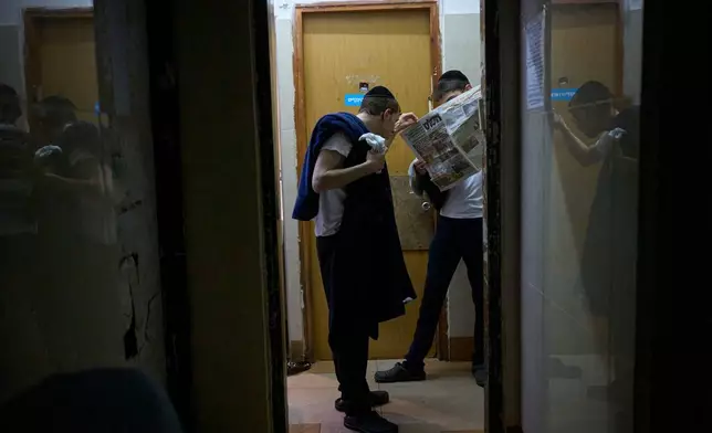Jewish seminary students read a newspaper in their room at Ponevezh Yeshiva in Bnei Brak, Israel, Tuesday, June 30, 2026. (AP Photo/Ohad Zwigenberg)