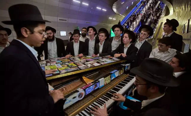 Ultra-Orthodox Jewish men play the piano before boarding a train in Jerusalem following a rally protesting plans to require them to serve in the Israeli military, Thursday, Oct. 30, 2025. (AP Photo/Ohad Zwigenberg)