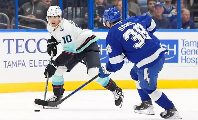 Seattle Kraken center Matty Beniers (10) moves the puck against Tampa Bay Lightning left wing Brandon Hagel (38) during the first period of an NHL hockey game Thursday, Oct. 15, 2026, in Tampa, Fla. (AP Photo/Chris O'Meara)