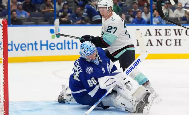 Tampa Bay Lightning goaltender Andrei Vasilevskiy (88) falls backwards after stopping a shot by Seattle Kraken center Berkly Catton (27) during the first period of an NHL hockey game Thursday, Oct. 15, 2026, in Tampa, Fla. (AP Photo/Chris O'Meara)
