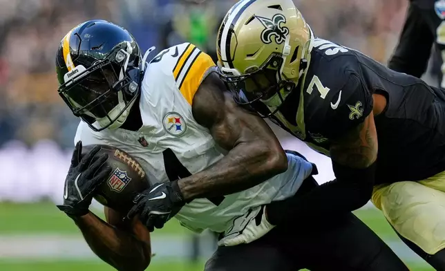 Pittsburgh Steelers wide receiver Dk Metcalf (4) catches the ball as New Orleans Saints safety Jonas Sanker (7) challenges during an NFL football game in Saint-Denis, outside Paris, Sunday, Oct. 25, 2026. (AP Photo/Steve Luciano)
