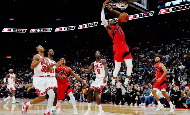 Toronto Raptors' RJ Barrett (9) dunks as Chicago Bulls' Caleb Wilson (8) and Isaac Okoro (35) look on during the second half of an NBA basketball game in Toronto, Wednesday, Oct. 21, 2026. (Frank Gunn/The Canadian Press via AP)
