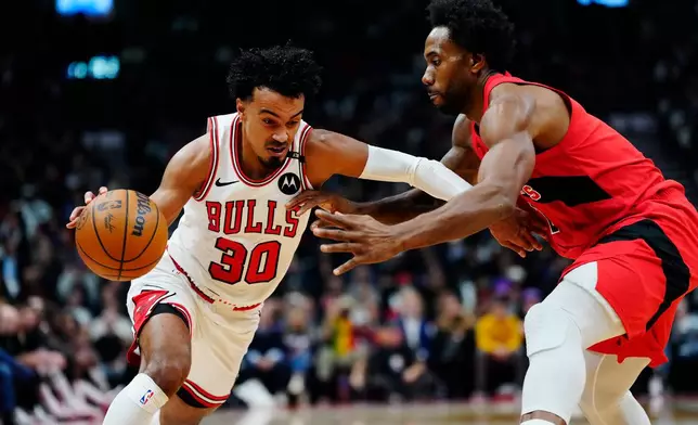 Chicago Bulls' Tre Jones (30) drives as Toronto Raptors' Kawhi Leonard (2) defends during the first half of an NBA basketball game in Toronto, Wednesday, Oct. 21, 2026. (Frank Gunn/The Canadian Press via AP)