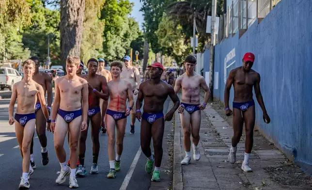 Men walk through the streets in purple swim briefs during an event to raise awareness about prostate cancer, in Johannesburg, Friday, Oct. 23, 2026. (AP Photo)