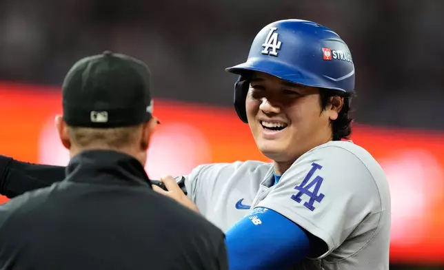 Los Angeles Dodgers' Shohei Ohtani, right, talks with umpire Tripp Gibson, left, at first during the eighth inning in Game 3 of baseball's National League Division Series against the Atlanta Braves, Tuesday, Oct. 6, 2026, in Atlanta. (AP Photo/Brynn Anderson)