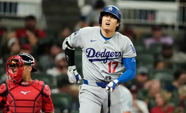 Los Angeles Dodgers' Shohei Ohtani reaches for his waist after taking a swing during an at-bat in the eighth inning in Game 3 of baseball's National League Division Series as Los Angeles Dodgers manager Dave Roberts kneels by the plate Tuesday, Oct. 6, 2026, in Atlanta. (AP Photo/Brynn Anderson)