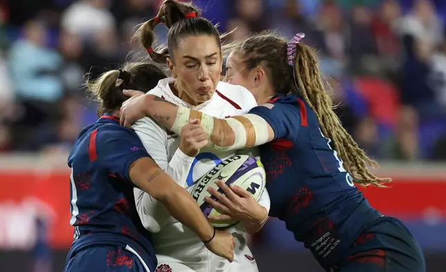 United States' Nina Mason, left, and Bella Vogel, right, tackle England's Holly Aitchison, center, during the second half of an international women's rugby match during the WXV Global Series, Friday, Oct. 30, 2026, in Harrison, N.J. (AP Photo/Pamela Smith)