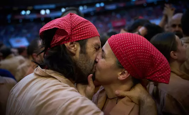 Rober and Neus, members of Xiquets de Reus, kiss after completing a "castell," or human tower, during the 30th Concurs de Castells, or Human Tower Competition in Tarragona, Spain, Sunday, Oct. 4, 2026. (AP Photo/Emilio Morenatti)