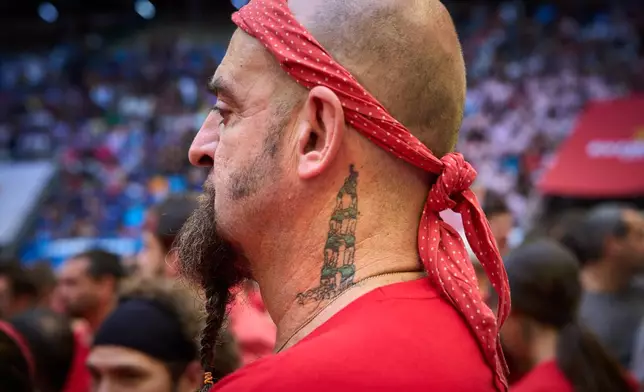 A member Castellers de Cerdanyola watches as another team forms a "castell," or human tower, during the 30th Concurs de Castells, or Human Tower Competition in Tarragona, Spain, , Sunday, Oct. 4, 2026. (AP Photo/Emilio Morenatti)