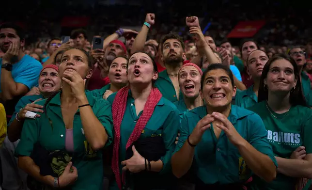 Members of Castellers de Sabadell react as another team forms a "castell" human tower during the 30th Concurs de Castells, or Human Tower Competition, in Tarragona, Spain, Saturday, Oct. 5, 2026. (AP Photo/Emilio Morenatti)