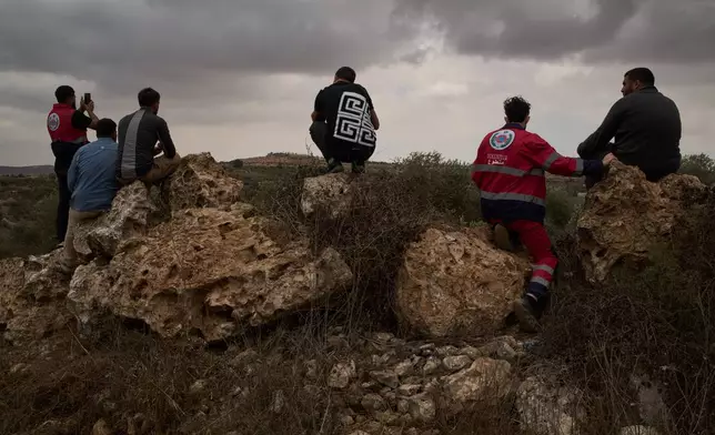 Palestinians look out for Israeli settlers as they takes part in a volunteer effort to protect local residents during the olive harvest in the West Bank town of Turmus Ayya, Sunday, Oct. 18, 2026. (AP Photo/Leo Correa)