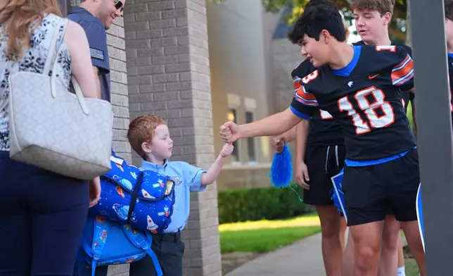 A high schooler greets an elementary school child on the first day of classes at Covenant Christian Academy in Colleyville, Texas, Wednesday, Aug. 12, 2026. (AP Photo/LM Otero)