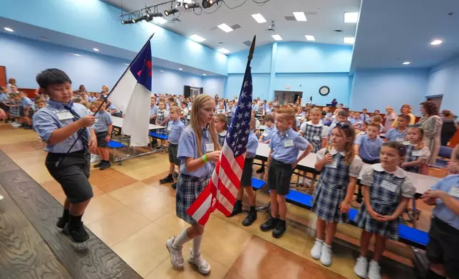 Children at Covenant Christian Academy carry flags during chapel in Colleyville, Texas, Wednesday, Aug. 12, 2026. (AP Photo/LM Otero)