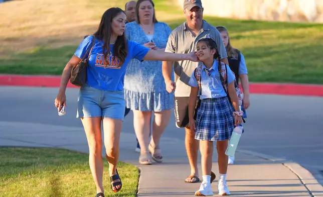 Parents and children walk together on the first day of classes at Covenant Christian Academy in Colleyville, Texas, Wednesday, Aug. 12, 2026. (AP Photo/LM Otero)