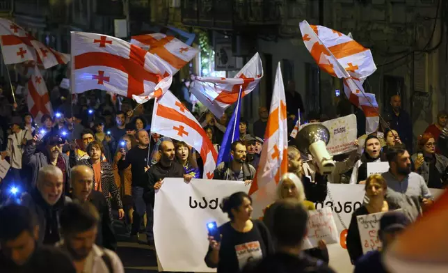 Demonstrators with national flags rally in the Georgian capital despite the harsh crackdown on dissent and tightened rules on public assemblies in Tbilisi, Georgia, Saturday, Oct. 17, 2026. (AP Photo/Zurab Tsertsvadze)