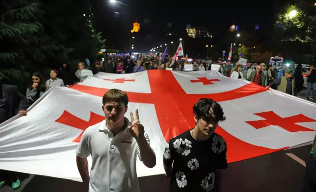 Demonstrators carry a Georgian national flag during a rally despite the harsh crackdown on dissent and tightened rules on public assemblies in Tbilisi, Georgia, Saturday, Oct. 17, 2026. (AP Photo/Zurab Tsertsvadze)