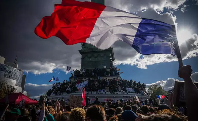 A person holds a French national flag during a protest against under-resourced schools in Paris, Thursday, Oct. 8, 2026. (AP Photo/Aurelien Morissard)