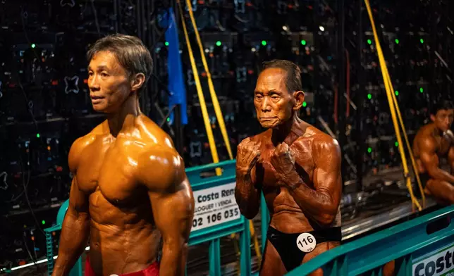 Japanese bodybuilder Toshisuke Kanazawa, 90, right, prepares to compete in the 2026 IFBB World Fitness and Bodybuilding Championships in Santa Susanna, Spain, Friday, Oct. 30, 2026. (AP Photo/Pau Venteo)