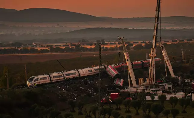 Cranes lift wrecked train carriages as rescuers search for victims following a collision between two trains in Urda, Spain, Thursday, Oct. 29, 2026. (AP Photo/Manu Fernandez)