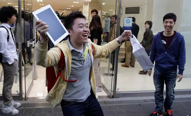 FILE - In this Friday, April 20, 2012, file photo, Baek Sung-min, 23, reacts after purchasing a new iPad at an Apple store in Seoul, South Korea. (AP Photo/Lee Jin-man)