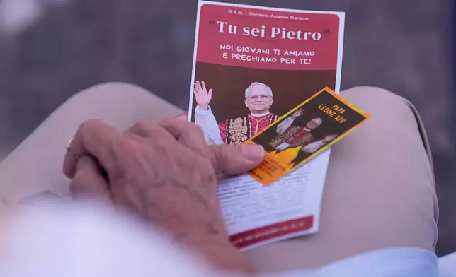 A woman holds photos of Pope Leo XIV as she prays at the Agostino Gemelli Polyclinic where the pontiff is hospitalised, in Rome, Thursday, Oct. 15, 2026. (AP Photo/Alessandra Tarantino)