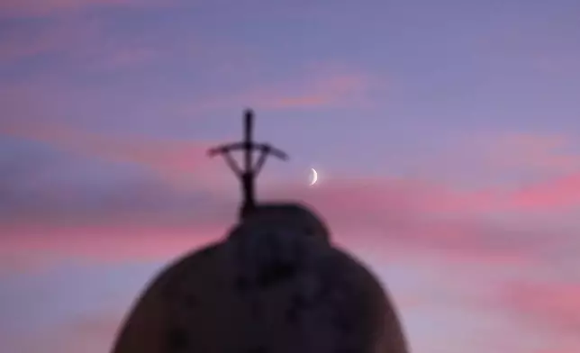 The moon rises behind the statue of late Pope St. John Paul II at the Agostino Gemelli Polyclinic where Pope Leo XIV is hospitalised, in Rome, Thursday, Oct. 15, 2026. (AP Photo/Alessandra Tarantino)