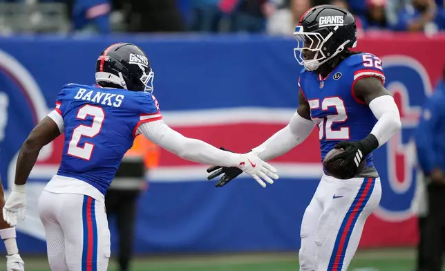 New York Giants linebacker Arvell Reese (52) celebrate his interception against the Arizona Cardinals with Giants cornerback Deonte Banks (2) during an NFL football game, in East Rutherford, N.J., Sunday, Oct. 4, 2026. (AP Photo/Seth Wenig)
