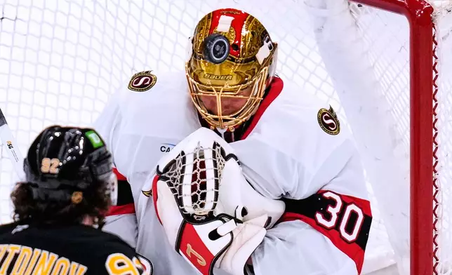 Ottawa Senators' Samuel Ersson (30) makes a save as Boston Bruins' Marat Khusnutdinov (92) looks for a rebound during the third period of an NHL hockey game, Monday, Oct. 5, 2026, in Boston. (AP Photo/Charles Krupa)