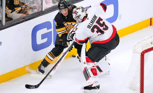 Boston Bruins' Matthew Poitras, left, knocks the puck away from Ottawa Senators' Linus Ullmark (35) during the second period of an NHL hockey game, Monday, Oct. 5, 2026, in Boston. (AP Photo/Charles Krupa)
