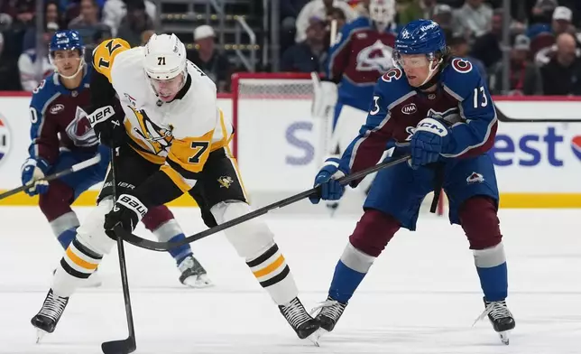 Pittsburgh Penguins center Evgeni Malkin (71) collects the puck as Colorado Avalanche right wing T.J. Hughes, right, defends in the first period of an NHL hockey game, Friday, Oct. 16, 2026, in Denver. (AP Photo/David Zalubowski)