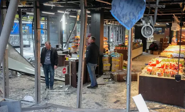 Employees examine the damage at a candy shop after a Russian missile strike in central Kyiv, Ukraine, Monday, Oct. 19, 2026. (AP Photo/Efrem Lukatsky)