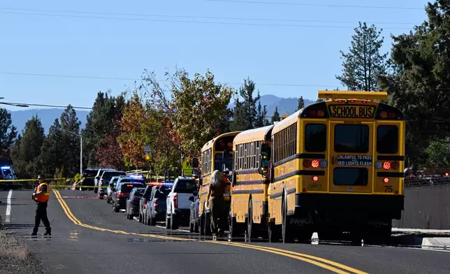 School buses are lined up outside Silver Rail Elementary school, where a shooting took place, on Thursday, Oct. 15, 2026 in Bend, Ore. (AP Photo/Joe Kline)