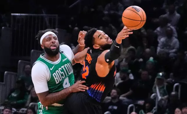 New York Knicks' Karl-Anthony Towns, right, reaches for a pass against Boston Celtics' Mitchell Robinson (4) during the first half of an NBA basketball game, Friday, Oct. 23, 2026, in Boston. (AP Photo/Charles Krupa)