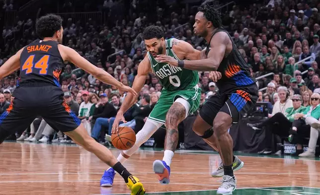 Boston Celtics' Jayson Tatum (0) is covered by New York Knicks' Og Anunoby, right, and Landry Shamet (44) on a drive to the basket during the first half of an NBA basketball game, Friday, Oct. 23, 2026, in Boston. (AP Photo/Charles Krupa)