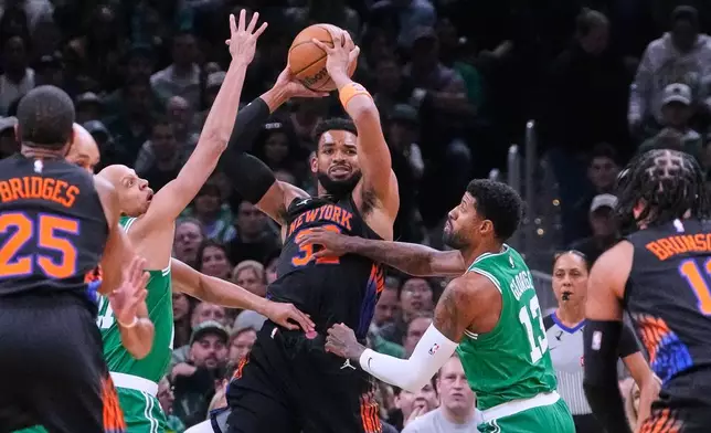 New York Knicks' Karl-Anthony Towns (32) looks to pass the ball while covered by Boston Celtics' Paul George (13) and Jordan Walsh, center left, during the first half of an NBA basketball game, Friday, Oct. 23, 2026, in Boston. (AP Photo/Charles Krupa)