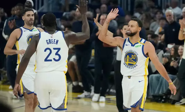 Golden State Warriors forward/center Draymond Green (23) celebrates with guard Stephen Curry (30) during the first half of an NBA basketball game against the Memphis Grizzlies, Friday, Oct. 23, 2026, in San Francisco. (AP Photo/Jeff Chiu)