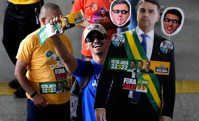 A supporter of presidential candidate Flavio Bolsonaro carries a cutout depicting him during a campaign event at central bus station in Brasilia, Brazil, Friday, Oct. 2, 2026. (AP Photo/Eraldo Peres)
