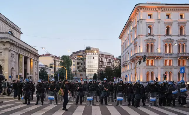 Anti-riot police watch people marching through the streets of Milan, Saturday, Oct. 24, 2026, to protest against the rising cost of living and deteriorating public services during one of several protests in Italy organized by groups across the political spectrum. (AP Photo/Antonio Calanni)