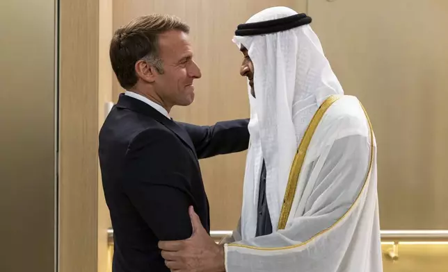 In this photograph released by the state-run WAM news agency, United Arab Emirates President Sheikh Mohammed bin Zayed Al Nahyan, right, greets French President Emmanuel Macron upon his arrival in Abu Dhabi, United Arab Emirates, Monday, Oct. 19, 2026. (WAM via AP)