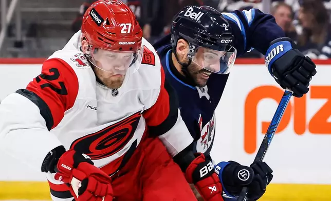 Winnipeg Jets' Dylan DeMelo (2) defends against Carolina Hurricanes' Nikolaj Ehlers (27) during the first period of an NHL hockey game in Winnipeg, Manitoba, Saturday, Oct. 17, 2026. (John Woods/The Canadian Press via AP)
