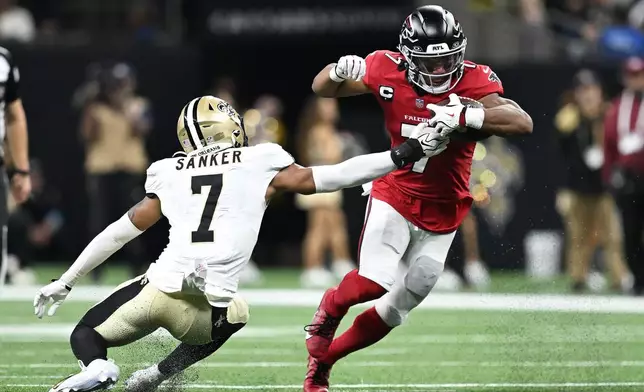 Atlanta Falcons running back Bijan Robinson, right, runs against New Orleans Saints safety Jonas Sanker during the first half of an NFL football game in New Orleans, Monday, Oct. 5, 2026. (AP Photo/Ella Hall)