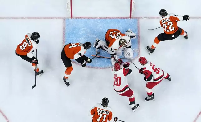 Carolina Hurricanes' Sebastian Aho (20) tries to get the puck past Philadelphia Flyers' Simon Benoit (44) and Joseph Woll (53) during the first period of an NHL hockey game Sunday, Oct. 11, 2026, in Philadelphia. (AP Photo/Matt Slocum)