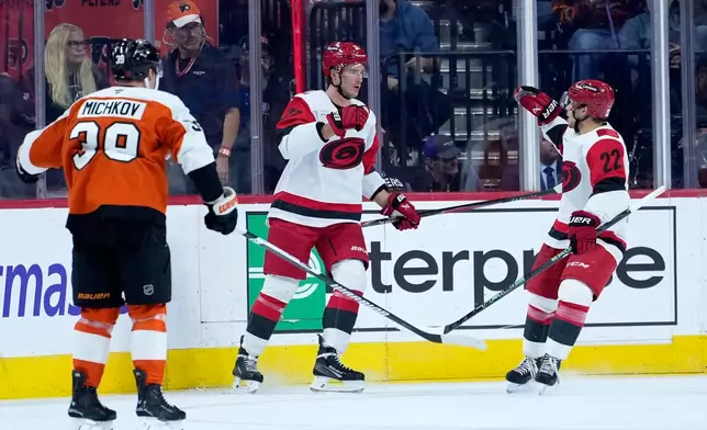 Carolina Hurricanes' Andrei Svechnikov, center, and Logan Stankoven, right, celebrate past Philadelphia Flyers' Matvei Michkov after Svechnikov's goal during the second period of an NHL hockey game Sunday, Oct. 11, 2026, in Philadelphia. (AP Photo/Matt Slocum)